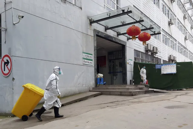In this Thursday, January 23, 2020, photo, a staff member wearing a hazardous materials suit hauls a bin at a hospital that reported a coronavirus death in Yichang in central China's Hubei Province. China is swiftly building a 1,000-bed hospital dedicated to patients infected with a new virus that has killed 26 people, sickened hundreds and prompted unprecedented lockdowns of cities during the country's most important holiday. (Photo by Chinatopix via AP Photo)