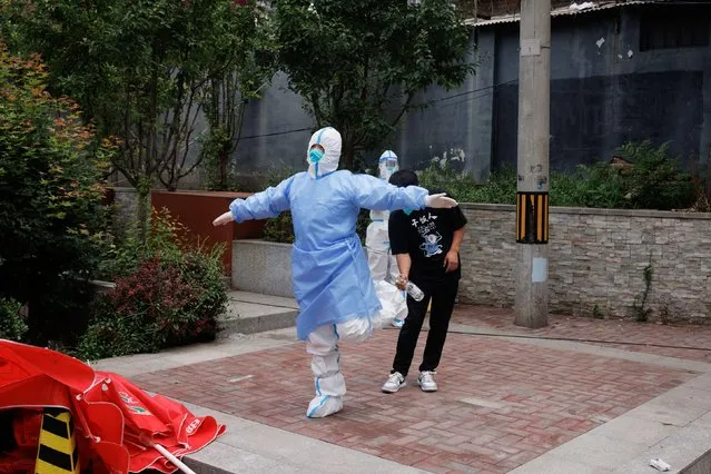 A man disinfects the personal protection suit of a medical worker at a nucleic acid testing station, following the coronavirus disease (COVID-19) outbreak, in Beijing, China, June 16, 2022. (Photo by Thomas Peter/Reuters)