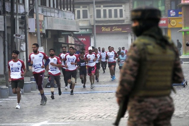 Indian paramilitary soldier guard as participants run during the Kashmir Marathon in Srinagar, Indian controlled Kashmir, Sunday, October 20, 2024. (Phoot by Mukhtar Khan/AP Photo)