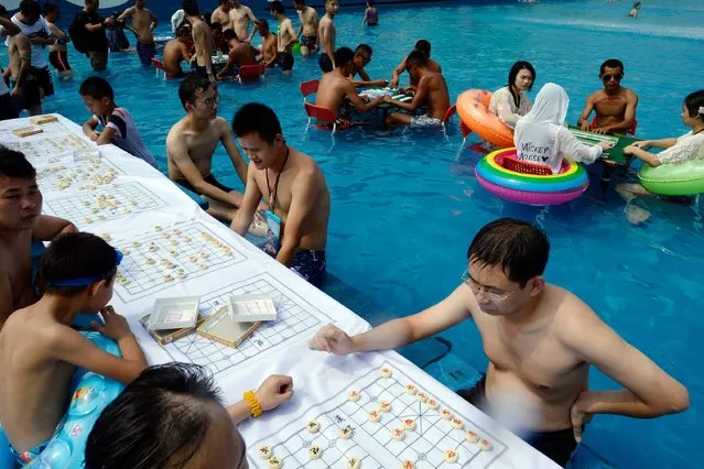 People play Chinese chess in a pool to escape the hot weather in Chongqing, southwest China on August 2, 2017. A red alert for high temperatures was issued on August 2 as temperatures reached 40 degrees in Chongqing. (Photo by AFP Photo/Stringer)