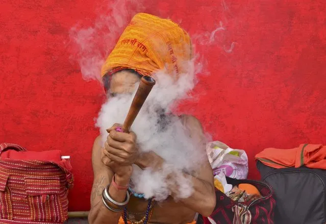 A Sadhu or a Hindu holyman smokes a pipe before registering for the annual pilgrimage to the Amarnath cave shrine, at a base camp in Jammu, June 30, 2016. (Photo by Mukesh Gupta/Reuters)