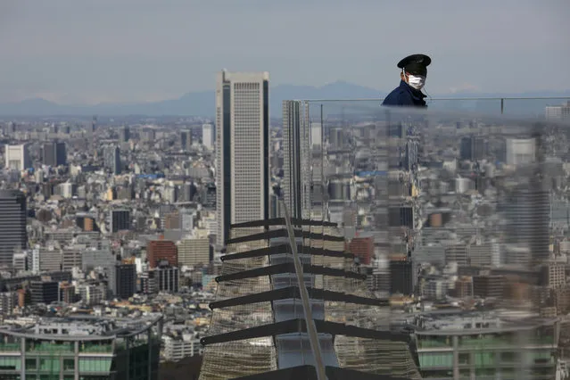 A security guard with a mask stands on Shibuya Sky observation deck in Tokyo, Tuesday, March 3, 2020. The Japanese government has indicated it sees the next couple of weeks as crucial to containing the spread of COVID-19, which began in China late last year. (Photo by Jae C. Hong/AP Photo)