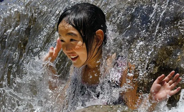 A child plays in the water fountain at Asuka park in Tokyo, on Jule 27, 2014. (Photo by Shizuo Kambayashi/Associated Press)