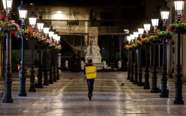 A deliveryman for Glovo rides an electric scooter in the empty Larios street during partial lockdown in downtown Malaga, southern Spain, March 15, 2020. (Photo by Jon Nazca/Reuters)