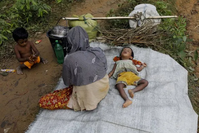 Newly arrived Rohingya refugees rest on the roadside after fleeing to Bangladesh from Myanmar in Ukhiya on September 6, 2017. More than 125,000 refugees have flooded across the border into Bangladesh. Most are Rohingya, a Muslim ethnic minority that the government of Buddhist-majority Myanmar largely does not recognise as citizens. (Photo by K.M. Asad/AFP Photo)