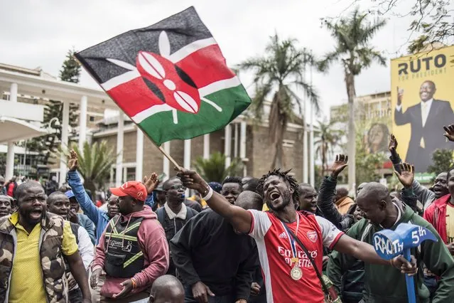An Azimio la Umoja political coalition supporter waves a Kenyan national flag while holding a hammer with RAO 5th (the name of Raila Odinga, Kenya's Azimio La Umoja Party presidential candidate) written on in Nairobi, on August 13, 2022. (Photo by Marco Longari/AFP Photo)