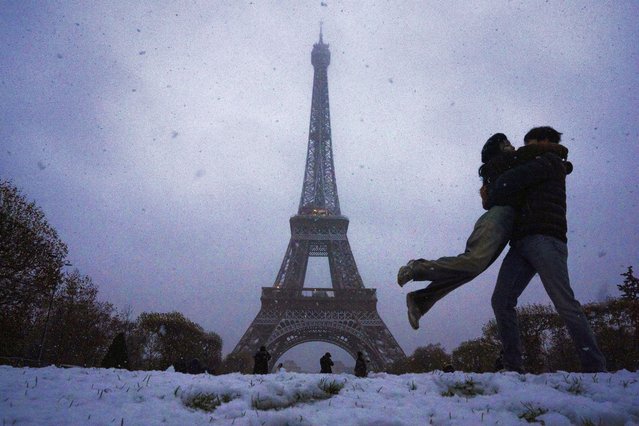 Visitors move as snow falls, with the Eiffel Tower in the background, in Paris, Thursday, November 21, 2024. (Photo by Louise Delmotte/AP Photo)