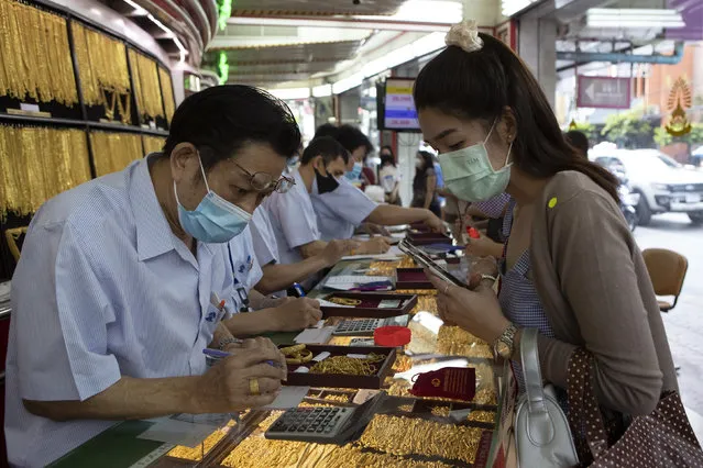 A Thai shopkeeper talks to customer who sold gold necklace to the gold shop in Bangkok, Thailand, Thursday, April 16, 2020. With gold prices rising to a seven-year high, many Thais have been flocking to gold shops to trade in their necklaces, bracelets, rings and gold bars for cash, eager to earn profits during an economic downturn. (Photo by Sakchai Lalit/AP Photo)