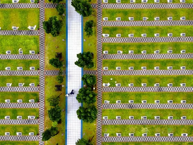Local people walk between tombs at a military cemetery in Xindian district, New Taipei City, on April 2, 2020. Taiwanese pay their respects to their ancestors during the Qinming Festival between April 2-6. (Photo by Sam Yeh/AFP Photo)