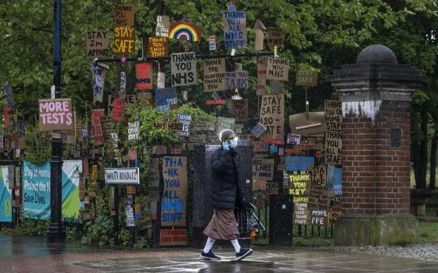 A member of the public (backlit by the photographers flash) walks past an display of signs put there by local artist Peter Liversidge on April 28, 2020 in London, United Kingdom. British Prime Minister Boris Johnson, who returned to Downing Street this week after recovering from Covid-19, said the country needed to continue its lockdown measures to avoid a second spike in infections. (Photo by Dan Kitwood/Getty Images)