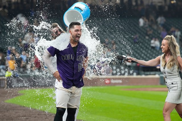 Colorado Rockies' Charlie Blackmon, back, douses Randal Grichuk as he is interviewed by field announcer Kelsey Wingert, right, following Grichuk's three-run home run off Milwaukee Brewers relief pitcher Taylor Rogers during the 10th inning of a baseball game Tuesday, September 6, 2022, in Denver. (Photo by David Zalubowski/AP Photo)