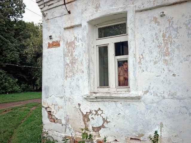 A woman sits in the window of a psychiatric facility for women. (Photo by Anastasia Rudenko)