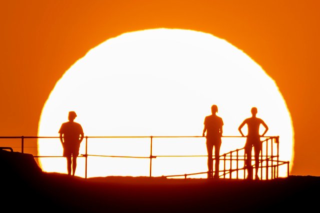 People watch as the sun rises over Ben Buckler Point in Bondi on November 27, 2024 in Sydney, Australia. Australians are at risk of enduring rolling blackouts this week, amid a heatwave sweeping through NSW and unexpected coal outages across the state. A severe heatwave warning has been issued by the Bureau of Meteorology for parts of eastern NSW over the next few days – with the mercury tipped to soar into the high 30s in some regions. Some areas reached a maximum temperature of 37C on Monday, with Richmond and Perth in Sydney's west also clocking in at 35C. (Photo by Brook Mitchell/Getty Images)