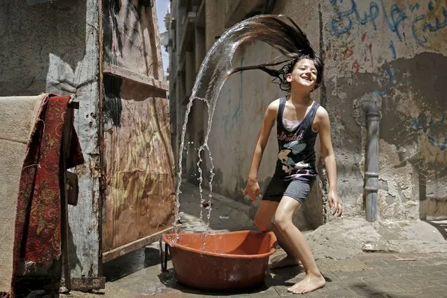 A Palestinian girl plays with water to cool off during a heatwave at Bureij refugee camp in the central Gaza Strip, amidst the COVID-19 pandemic on May 19, 2020. Across the Mediterranean with its tantalising beaches, a record heatwave has hit countries just as they cautiously ease COVID-19 lockdowns, stoking hopes the new season will help fight the virus. (Photo by Mohammed Abed/AFP Photo)