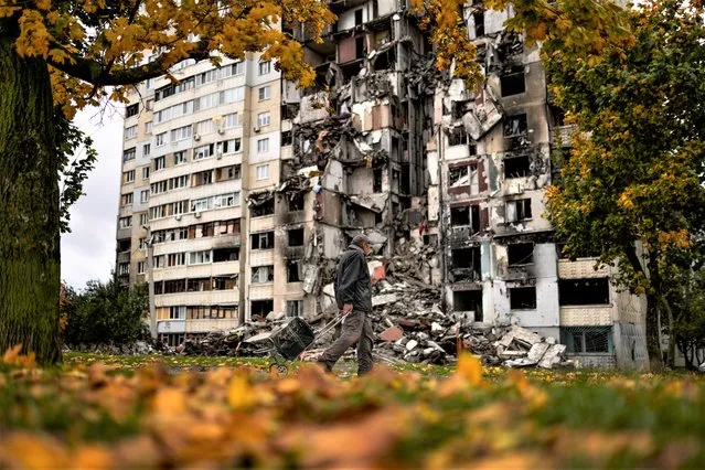 A man walks past a partially destroyed residential building at Saltivka neighbourhood in Kharkiv, Ukraine, Monday, October 3, 2022. (Photo by Francisco Seco/AP Photo)