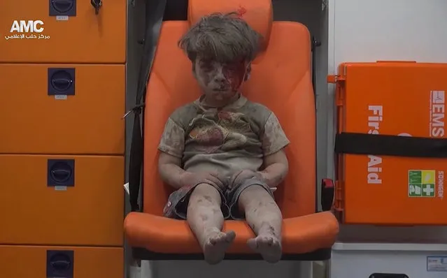 In this frame grab taken from video provided by the Syrian anti-government activist group Aleppo Media Center (AMC), a child sits in an ambulance after being pulled out or a building hit by an airstirke, in Aleppo, Syria, Wednesday, August 17, 2016. Syrian opposition activists reported an airstrikes on the al-Qaterji neighborhood in Aleppo late Wednesday. (Photo by Aleppo Media Center via AP Photo)