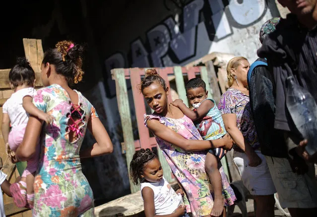 Residents gather for lunch donations outside an occupied building in the Mangueira “favela” community on August 13, 2016 in Rio de Janeiro, Brazil. (Photo by Mario Tama/Getty Images,)