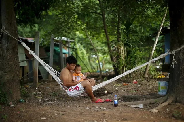 A man with a baby sits outside their house in a village near Udon Thani, Thailand, September 15, 2015. (Photo by Jorge Silva/Reuters)