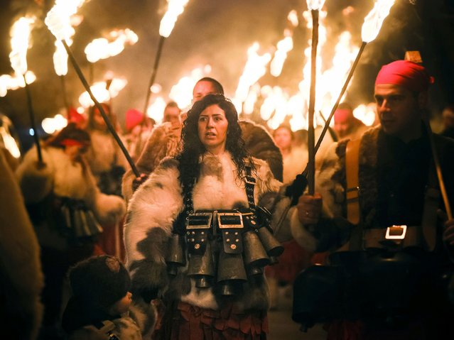 Bulgarians brave the freezing temperatures as they carry torches while celebrating an ancient Surva ritual in the village of Donna Sekirna, Bulgaria, south of the capital Sofia, late Saturday, January 13, 2024. The authentic pagan festival, called Surva, is held every year on the 13th and 14th of January in the western part of Bulgaria to mark the New Year. Surva is performed by costumed men, some in sheepskin or other colorful garments, bells, and masks, who walk around and dance to scare away the evil spirits in the hopes of providing a good harvest, health, fertility, and happiness. (Photo by Valentina Petrova/AP Photo)