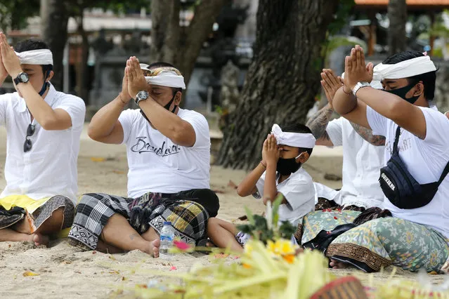 Balinese men pray during a ritual at Kuta beach, Bali, Indonesia on Thursday, July 9, 2020. Indonesia's resort island of Bali reopened after a three-month virus lockdown Thursday, allowing local people and stranded foreign tourists to resume public activities before foreign arrivals resume in September. (Photo by Firdia Lisnawati/AP Photo)