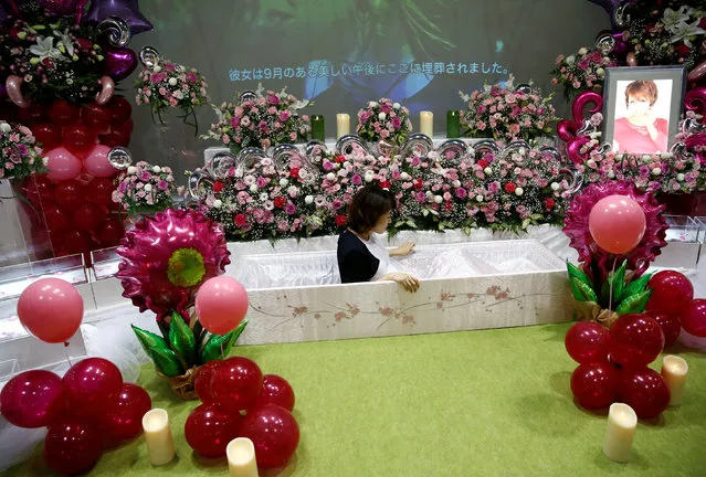 A staff sits in a casket next an altar decorated with flowers and balloons as she demonstrates Okuribito funeral's funeral service at the Life Ending Industry Expo in Tokyo, Japan, August 22, 2016. (Photo by Kim Kyung-Hoon/Reuters)