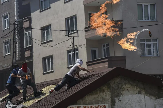 A left-wing militant throws a Molotov cocktail during clashes with Turkish riot police in Istanbul's Gazi district, on July 26, 2015. Tensions across the country are high, with police routinely using water cannon to disperse nightly protests in Istanbul and other cities denouncing IS and the government's policies on Syria. Turkey has launched a two-pronged "anti-terror" cross-border offensive against Islamic State (IS) jihadists and Kurdistan Workers Party (PKK) militants after a wave of violence in the country, pounding their positions with air strikes and artillery. But the expansion of the campaign to include not just IS targets in Syria but PKK rebels in neighbouring northern Iraq – themselves bitterly opposed to the jihadists – has put in jeopardy a truce with the Kurdish militants that has largely held since 2013. (Photo by Bulent Kilic/AFP Photo)
