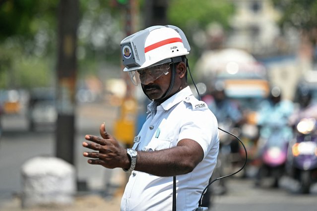 A traffic policeman uses an air-conditioned helmet to get respite from the heat while working at a road junction on a hot summer day in Chennai on April 8, 2025. India can expect hotter-than-usual temperatures this summer with more heatwave days taking a toll on lives and livelihoods, the weather office warned. (Photo by R.Satish Babu/AFP Photo)