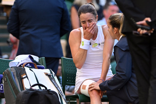 France's Alize Cornet reacts as she is tended by a physio after resulting injured during her women's singles tennis match against Kazakhstan's Elena Rybakina on the fourth day of the 2023 Wimbledon Championships at The All England Tennis Club in Wimbledon, southwest London, on July 6, 2023. (Photo by Glyn Kirk/AFP Photo)