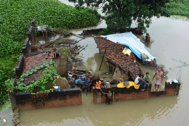An Indian family sit at their destroyed house amidst the floodwaters after heavy rains in Gaya in eastern Bihar state on September 6, 2016. The flood toll in Bihar went up to 204 even as the water levels of the overflowing Ganges river receded, according to a Disaster Management Department report. (Photo by AFP Photo/Stringer)