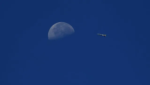 A fighter jet belonging to forces of Syria's President Bashar al-Assad flies in the sky, as the moon is seen in the background, from the town of Morek in Hama province July 18, 2014. (Photo by Rasem Ghareeb/Reuters)