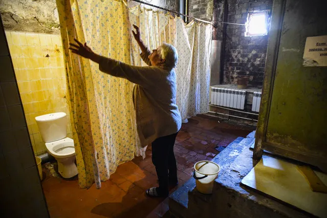 A woman adjusts a curtain in communal toilet in a dormitory for the workers of Proletarka textile factory in the town of Tver, 200 kilometres north-west from Moscow on August 8, 2020. (Photo by Andrey Borodulin/AFP Photo)