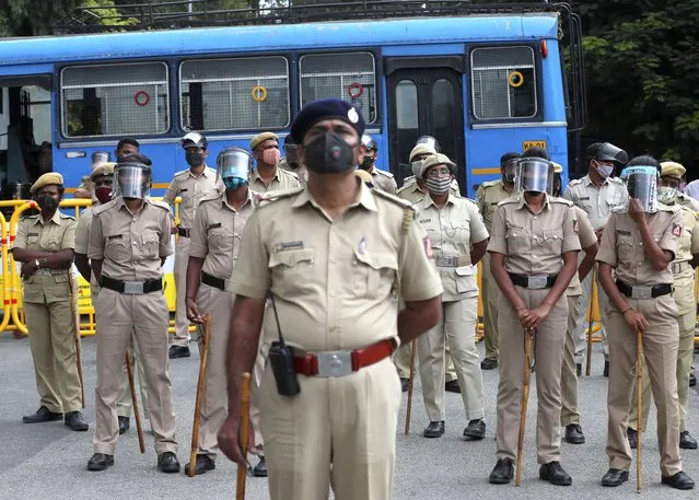 Indian police officials wearing face shields and masks as a precaution against the coronavirus stand guard during a protest against a pair of controversial agriculture bills in Bengaluru, India, Monday, September 28, 2020. India's confirmed coronavirus tally has reached 6 million cases, keeping the country second to the United States in number of reported cases since the pandemic began. (Photo by Aijaz Rahi/AP Photo)