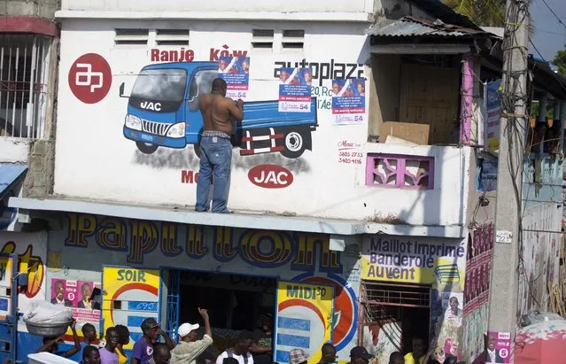 In this September 21, 2016 photo, a man pastes a campaign poster showing Haiti's ousted President Jean Bertrand-Aristide with presidential candidate Maryse Narcisse as the two campaign in the area in Port-au-Prince, Haiti. Although Aristide said he wouldn’t focus on politics after he returned from exile in 2011, the twice-elected, twice-ousted leader has been campaigning for Maryse Narcisse, the presidential candidate for his Fanmi Lavalas party. Haiti will hold elections on October 9. (Photo by Dieu Nalio Chery/AP Photo)