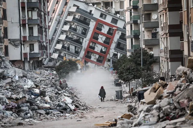 A woman walks in front of a collapsed building while demolition teams work after a powerful earthquake in Hatay, Turkey, 17 February 2023. Almost 44,000 people have died and thousands more are injured after two major earthquakes struck southern Turkey and northern Syria on 06 February. Authorities fear the death toll will keep climbing as rescuers look for survivors across the region. (Photo by Sedat Suna/EPA)