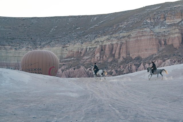 Hot air balloons rise as people ride horse at Cappadocia, which held a special place for horses throughout history, in Nevsehir, Turkiye on June 29, 2025. Visitors to the region can join guided horseback tours held in the wide valleys, especially during morning and evening hours. Located within the borders of Nevehir, Cappadocia stands out not only for its natural formations but also for its rich cultural heritage. (Photo by Ayten Altintas/Anadolu via Getty Images)