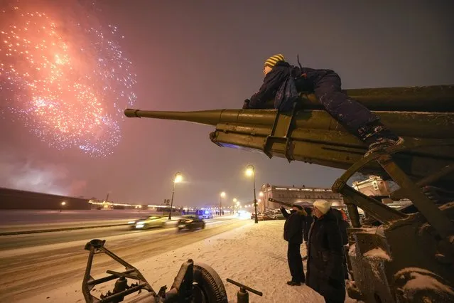 A boy watches fireworks from a military range weapon, marking the Defender of the Fatherland Day celebrations, at the Artillery Museum in St. Petersburg, Russia, Thursday, February 23, 2023. (Photo by Dmitri Lovetsky/AP Photo)
