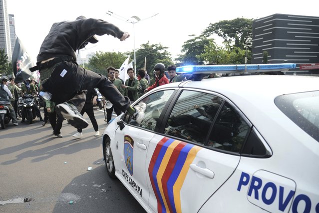 A student attacks a police car during a protest following the death of a delivery rider who was run over by a police armored vehicle in a rally against lawmakers' privilege, in Jakarta, Indonesia, Friday, August 29, 2025. (Photo by Tatan Syuflana/AP Photo)