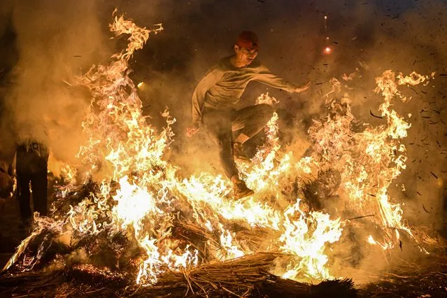 People jump cross the bonfire on February 28, 2023 in Jieyang,Guangdong Province of China.The citizens held a fire jumping activity to pray for the elimination of bad luck. (Photo by John Ricky/Anadolu Agency via Getty Images)