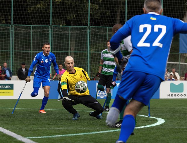 The goalie for the Zhytomyr Titans team grabs the ball as Lviv Pokrova AMP team (blue uniform) attack during a tournament game on September 28, 2025 in Lviv, Ukraine. The Ukrainian Association of Football (UAF) launched the Ukrainian Amputee Football Championship with the second round tournament taking place Saturday and Sunday. The “League of the Mighty” supports people with amputations or impaired function of one limb promoting a return to active life finding inspiration through sport. In just one year, adaptive football in Ukraine has grown from a few amateur teams into a large-scale national championship featuring 10 teams from all over Ukraine. (Photo by Paula Bronstein /Getty Images)