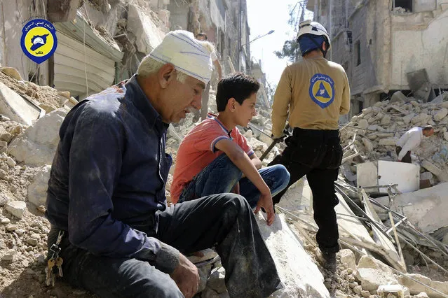 In this picture taken, Tuesday, October 11, 2016, provided by the Syrian Civil Defense group known as the White Helmets, residents sit amongst rubble in rebel-held eastern Aleppo, Syria. (Photo by Syrian Civil Defense- White Helmets via AP Photo)