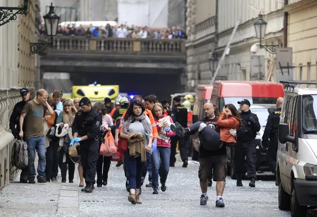 Injured people leave a scene of an explosion in downtown Prague, Czech Republic, Monday, April 29, 2013. Police said a powerful explosion has damaged a building in the center of the Czech capital and they believe some people are buried in the rubble. (Photo by Petr David Josek/AP Photo)