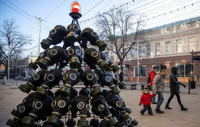 People walk past a Christmas tree made of gas masks in Ryazan, Russia on December 12, 2020. (Photo by Maxim Shemetov/Reuters)