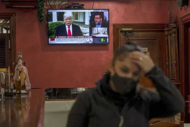 A waiter gestures in front a TV screen broadcasting news reports on U.S. President Donald Trump, in Rivas Vaciamadrid, Spain, Thursday, January 7, 2021. Congress confirmed Democrat Joe Biden as the presidential election winner early Thursday after a violent mob loyal to President Donald Trump stormed the U.S. Capitol in a stunning attempt to overturn America's presidential election. (Photo by Manu Fernandez/AP Photo)