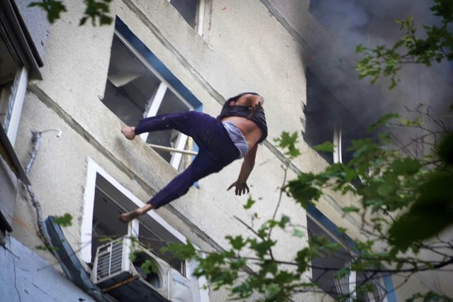 A man falls down to death from a burning apartment window after Russia's guided air bomb strike in Kharkiv, Ukraine, Friday, August 30, 2024. Russian attack on the northeastern city of Kharkiv using powerful plane-launched glide bombs killed five people, including a 14-year-old girl on a playground, and wounded 47 others, regional Gov. Oleh Syniehubov said. (Photo by Andrii Marienko/AP Photo)