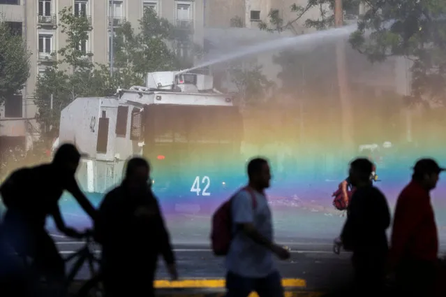 A water cannon is used by police to spray demonstrators taking part in a rally on the third anniversary of the protests and riots that rocked the country in 2019, in Santiago, Chile on October 18, 2022. (Photo by Ivan Alvarado/Reuters)