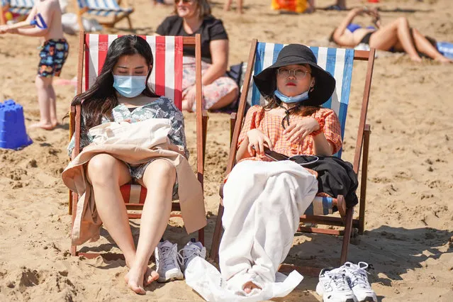 Sunbathers wearing face masks while sitting on deck chairs at South Bay beach during the hot weather on July 31, 2020. The UK is set to bask as temperatures will reach 36 degrees Celsius in the capital during a mini heat wave. (Photo by Yiannis Alexopoulos/SOPA Images/Sipa USA/LightRocket via Getty Images)