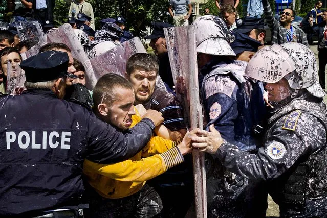 Police, who were splashed with paint, scuffle with hard line opposition members in Pristina, Kosovo,  protesting an agreement by lawmakers to normalize relations with Serbia, on June 27, 2013. (Photo by Visar Kryeziu/Associated Press)