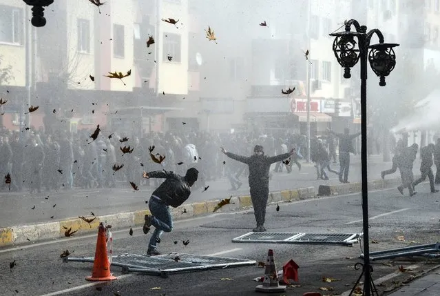 Kurds clash with the Turkish police as they protest against the recent curfews imposed on Kurdish towns, on December 14, 2015, in downtown Diyarbakir. 
The Turkish authorities on December 11, lifted a nine-day curfew on the central Sur district in the southeastern city of Diyarbakir, the main city of Turkey's Kurdish-majority southeast, after heavy fighting with Kurdish militants  but then promptly reimposed the measure. (Photo by Ilyas Akengin/AFP Photo)