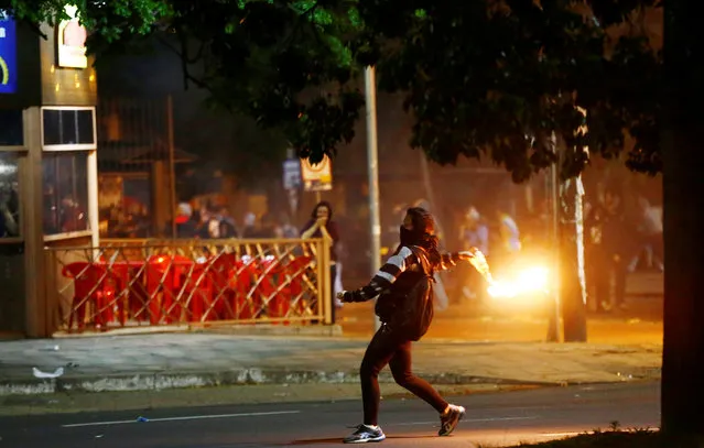 A woman prepares to throw a molotov cocktail towards to police officers during a demonstration against a constitutional amendment, known as PEC 241, that would limit public spending, in Porto Alegre, Brazil, November 11, 2016. (Photo by Lunae Parracho/Reuters)