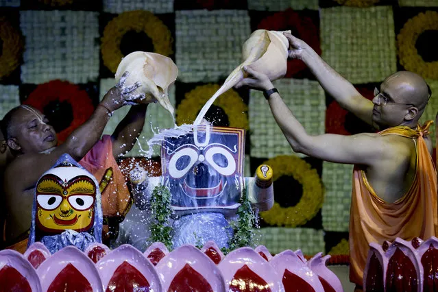 In this Thursday, June 28, 2018, file photo, Hindu priests pour milk on idols of deities Lord Jagannath, Balabhadra and Subhadra during the holy “Snan Yatra” or bathing ceremony in Kolkata, India. The ritual was held ahead of ahead of the annual chariot procession scheduled for July 14. (Photo by Bikas Das/AP Photo/File)
